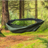 DD Frontline Hammock in the forest, showcasing its durable design and built-in mosquito net for outdoor comfort.